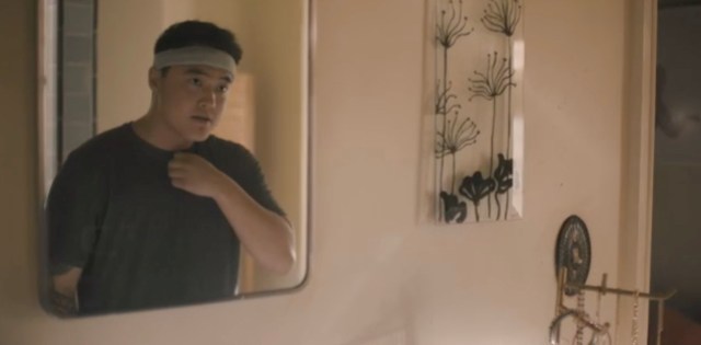 Leo looks in the bathroom mirror in a t-shirt with a sweatband