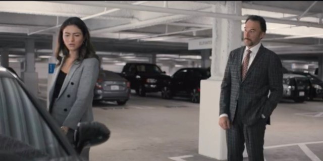 In a parking garage, Dani is about to open her cardoor. Her father, in a suit, stops her.