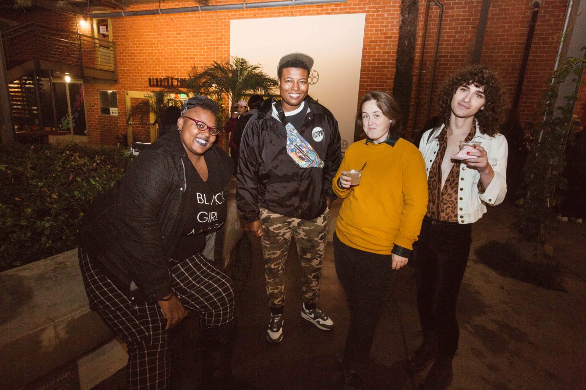 Four people pose for a photo outside. 