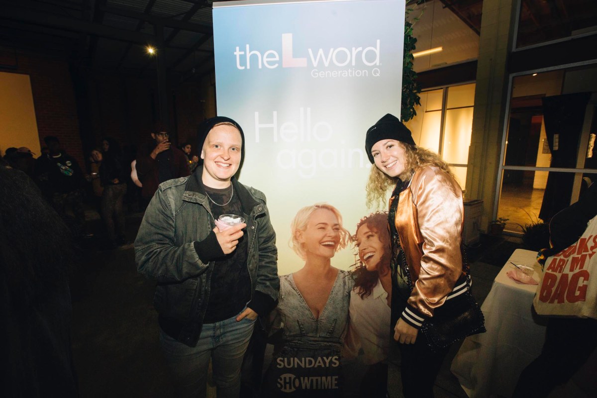 Two people take a picture in front of a banner advertising "The L Word: Generation Q."