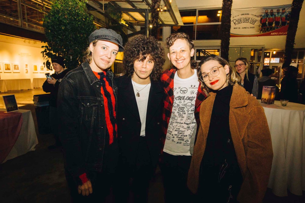 Four people pose for a photo inside at a party reception area.