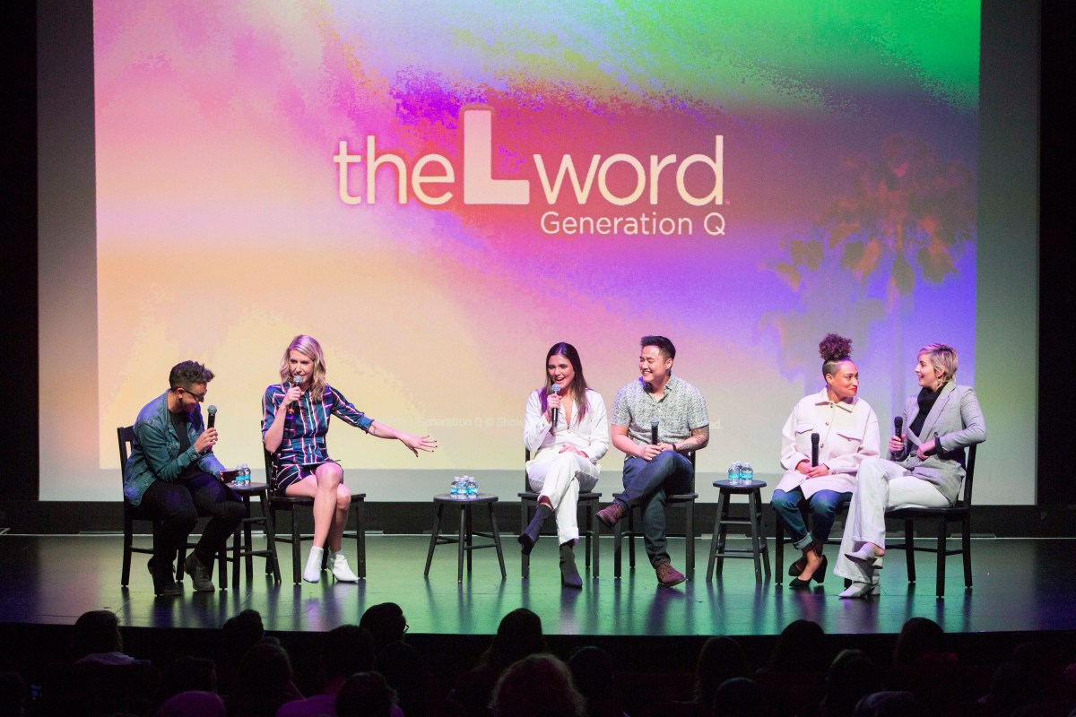 Carly and Riese on stage next to Arienne Mandi (Dani), Leo Sheng (Micah), Rosanny Zayas (Sophie) and Jacqueline Toboni (Finley). The screen in the background has the logo for "The L Word: Generation Q" projected onto it.