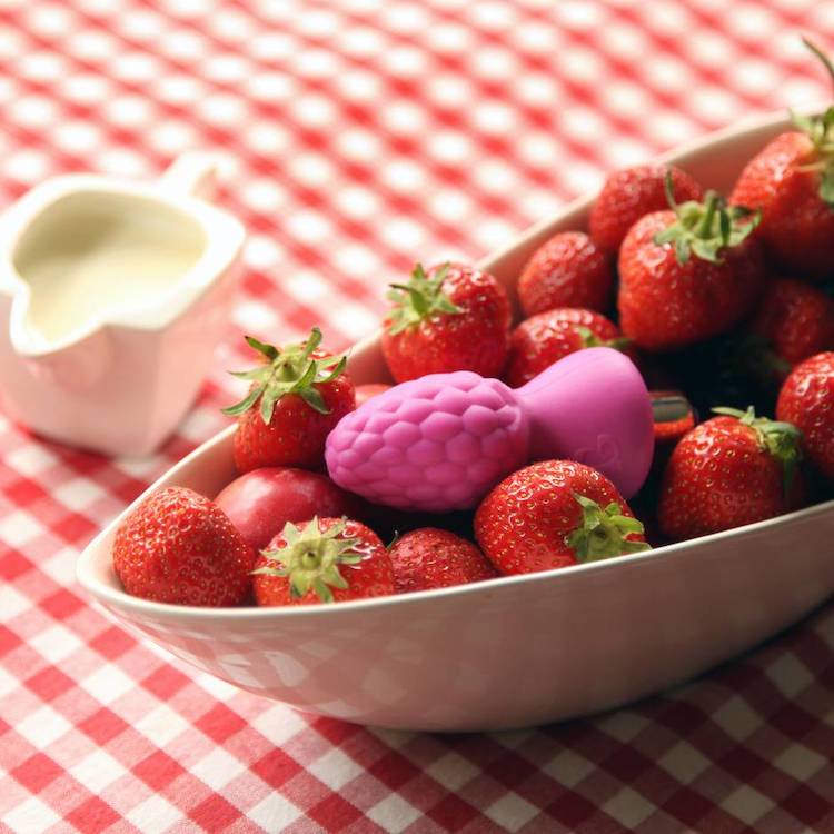 a butt plug shaped like a berry in a bowl of strawberries