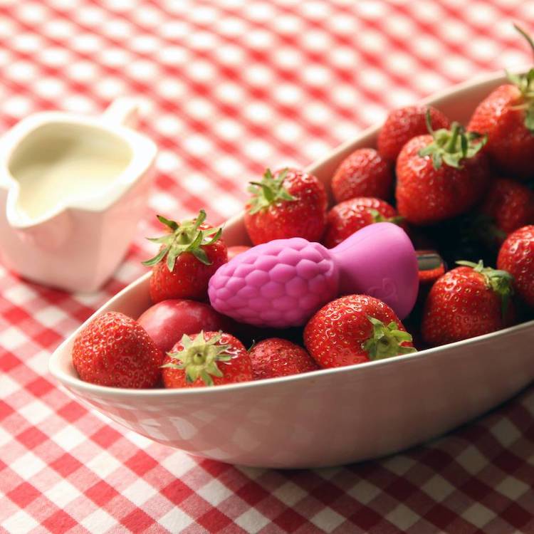 a butt plug shaped like a berry in a bowl of strawberries