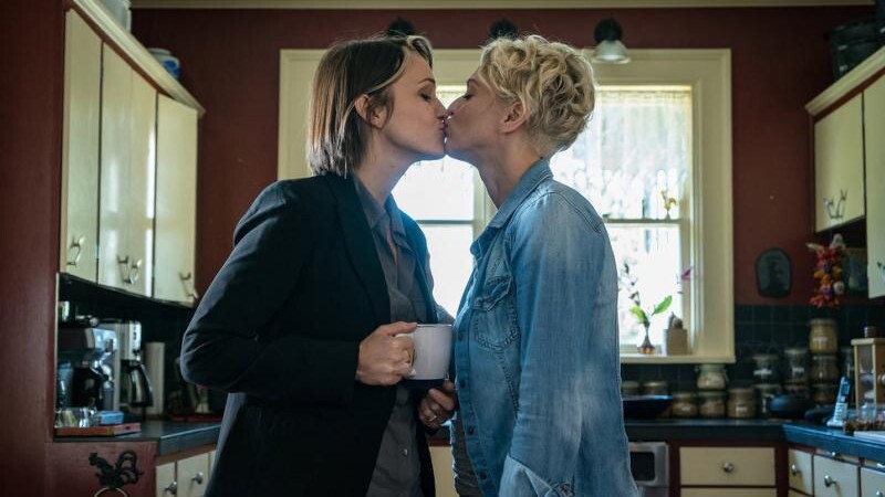Val and Marilyn McGrath-Dufresne kiss with coffee in hand