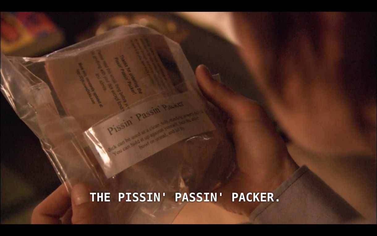 Max is holding in his hands a plastic wrapper that reads "Pissin' Passin' Packer"