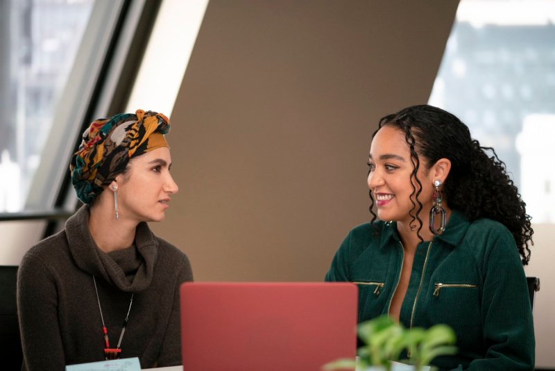 Kat and Adena work together on a laptop in the Scarlet Magazine offices.