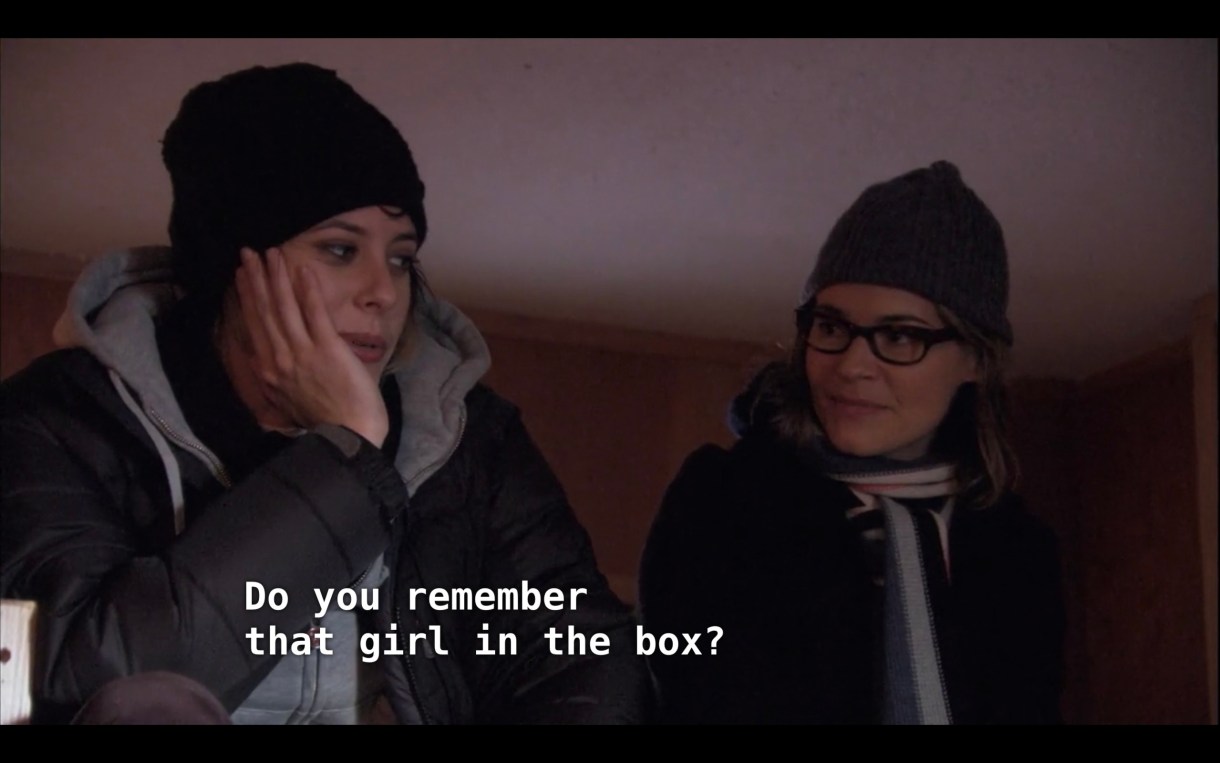 Shane (wearing a black beanie, a grey hoodie under a black jacket) sits next to Alice (wearing a dark beanie and a striped neck scarf). Shane asks, "Do you remember that girl in the box?"