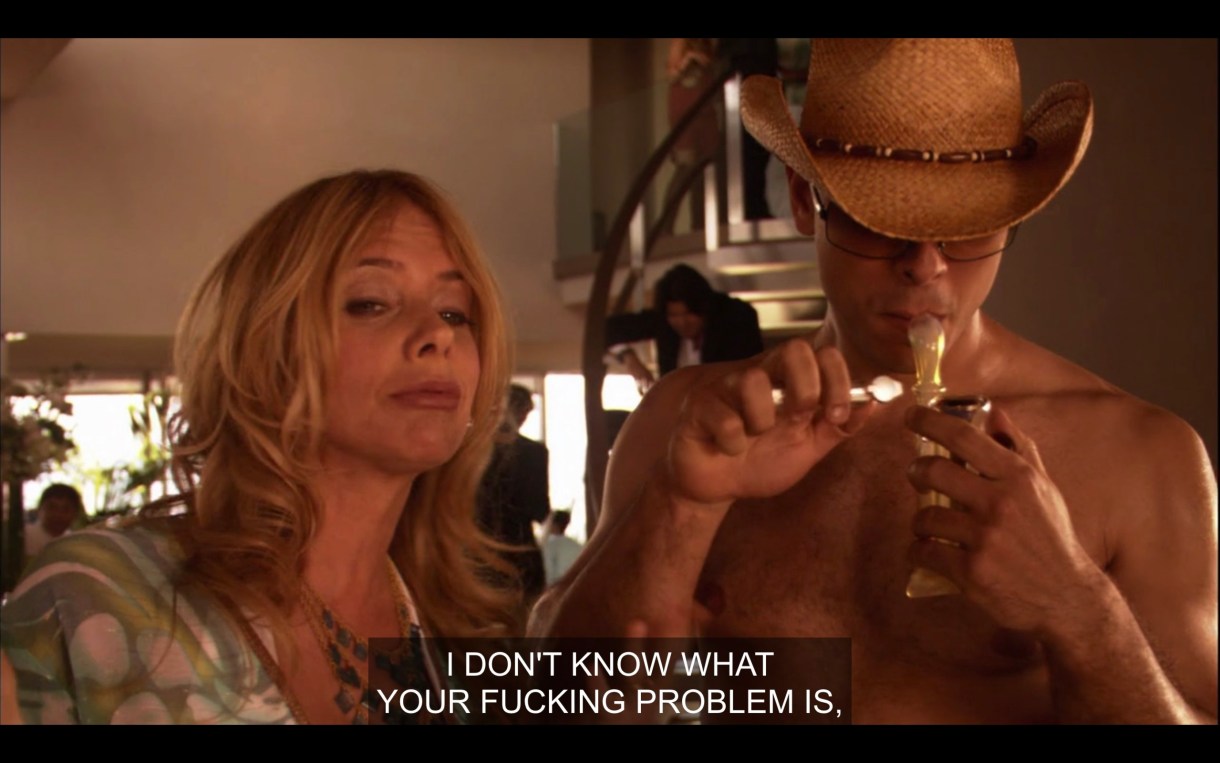 Cheri stands next to a topless guy wearing a cowboy hat and lighting a bong. Cheri says to Shane, who is off screen, "I don't know what your fucking problem is" 