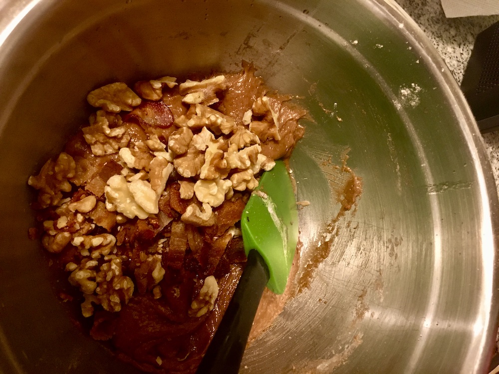 cookie dough with walnuts and bcaon chunks being folded in with a spatula