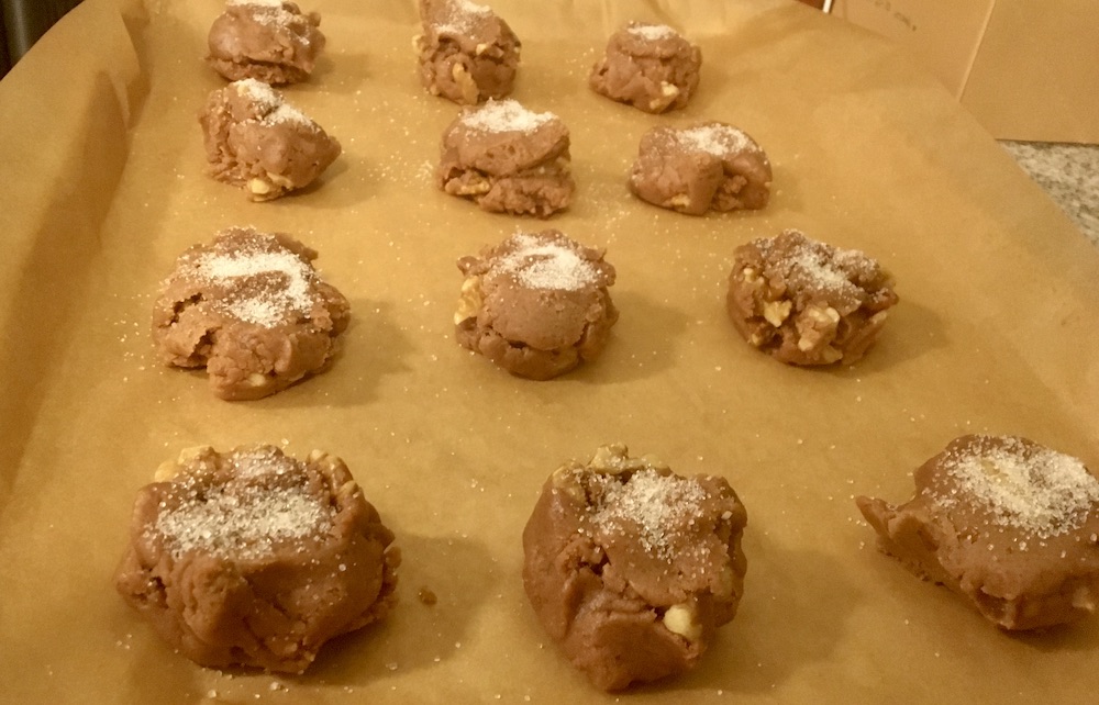 cookie dough balls lined up on a baking sheet with sugar on top