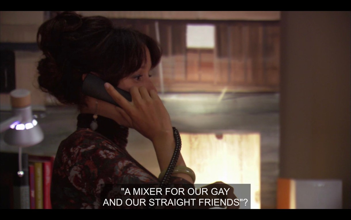 Bette's talking on the phone in her office. She asks, "A mixer for our gay and our straight friends?"