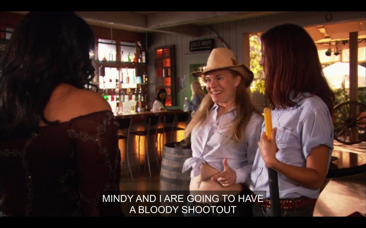 Two waitresses at the Planet, one wearing a cowboy hat, the other holding a broom. One of them says, "Mindy and I are going to have a bloody shootout."