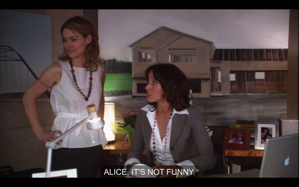 Alice stands next to Bette, who is sitting at her desk in her office. Bette says, "Alice, it's not funny," referring to Phyllis' crush on Alice.