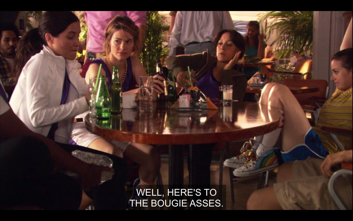 Helena, Alice, Bette, and Jenny sit around a round table at The Planet after the basketball game. Bette raises her glass for a toast and says, "Well, here's to the bougie asses."