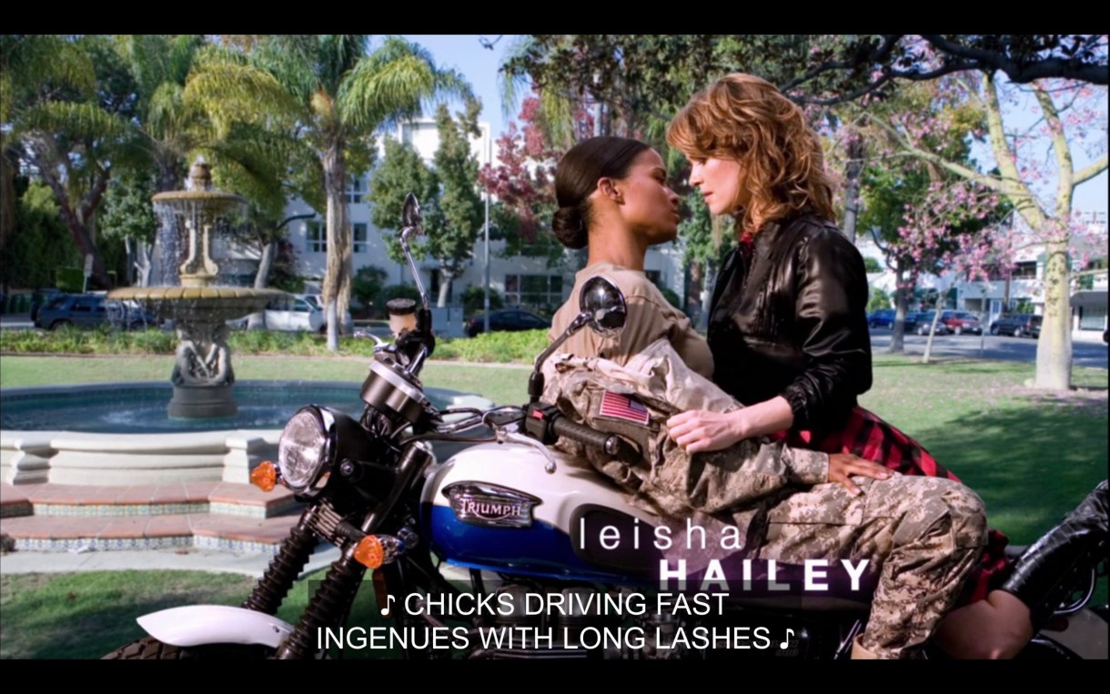 Tasha and Alice leaning in for a kiss on a motorcycle during the theme song. Subtitles read, "Chicks driving fast ingenues with long lashes."