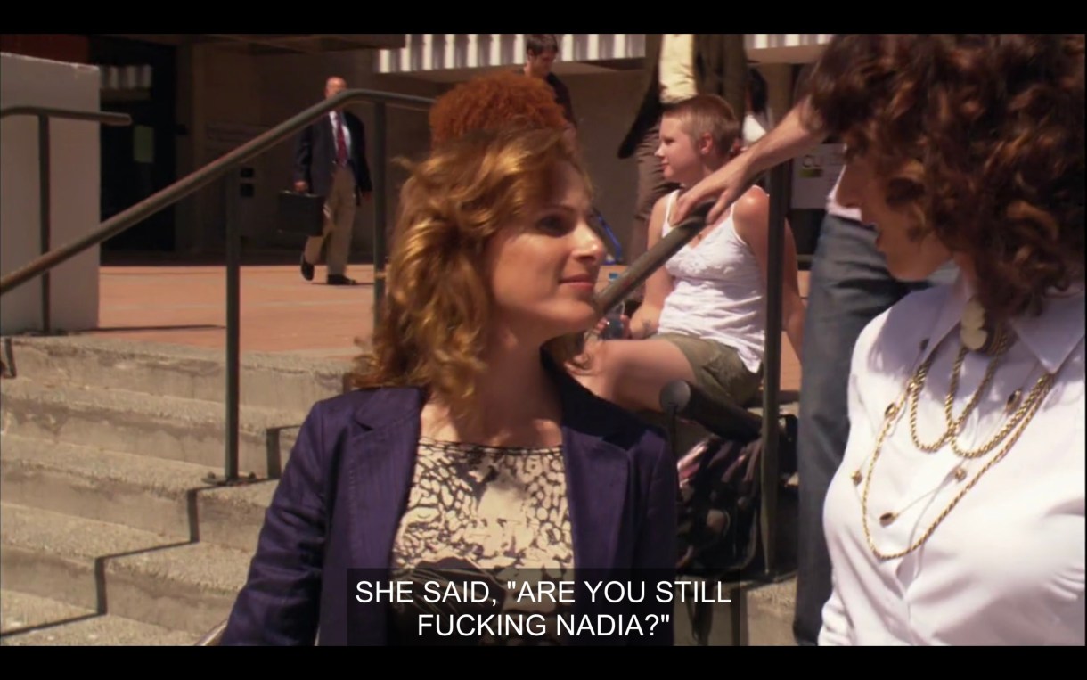 Jodi (in a blue blazer) and Bette (in a white blouse with a gold necklace) standing outside on concrete steps. "She said, 'Are you still fucking Nadia?'"