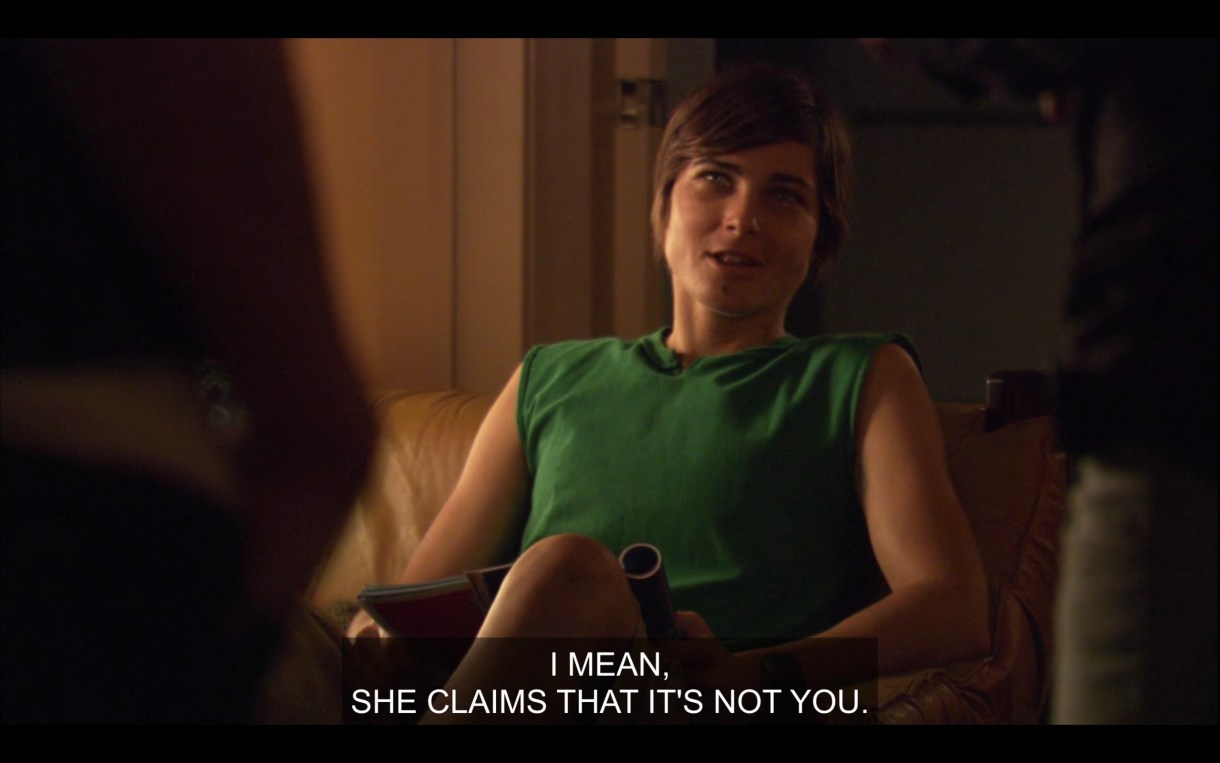 Max sits on a chair in the living room wearing a green cut-off shirt. He says, "I mean, she claims that it's not you."