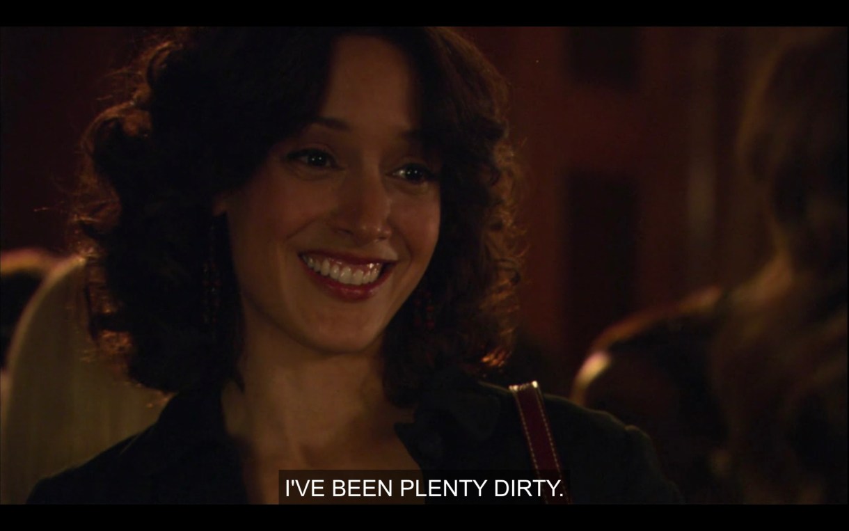 Bette (in a black blazer) smiles and says, "I've been plenty dirty."