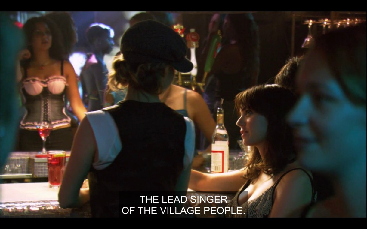 Alice and Jenny stand in a crowded bar. Jenny says, "The lead singer of the village people."