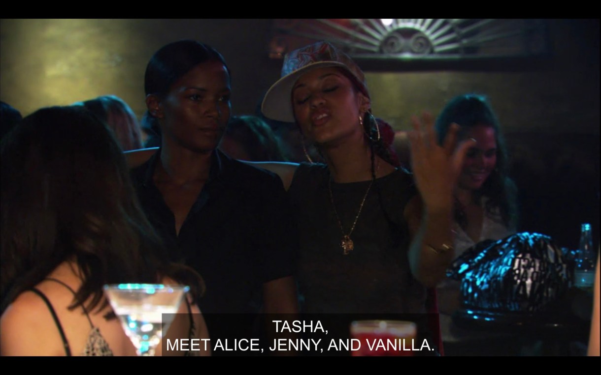 Papi has her hand around Tasha's shoulder in a crowded bar. Papi says, "Tasha, meet Alice, Jenny, and Vanilla."