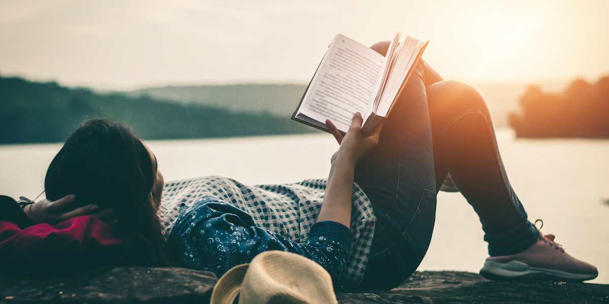 person reading on a dock outside at sunset