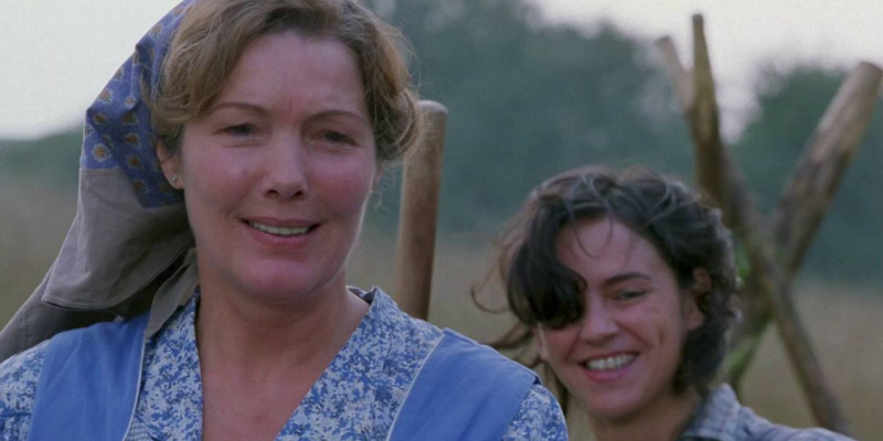 A middle aged woman in a blue bonnet stands in front of a younger woman.