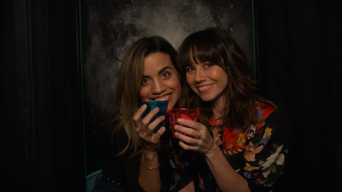 Image: Judy is in a photobooth with drinks and her girlfriend, played by Natalie Morales. They are smiling.