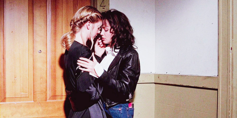 Angelina Jolie and Elizabeth Mitchell kiss against a wooden door.