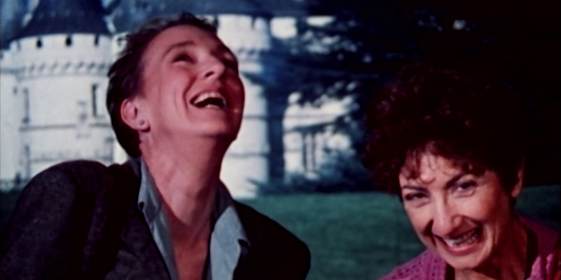 Two older women with short hair laugh next to each other.