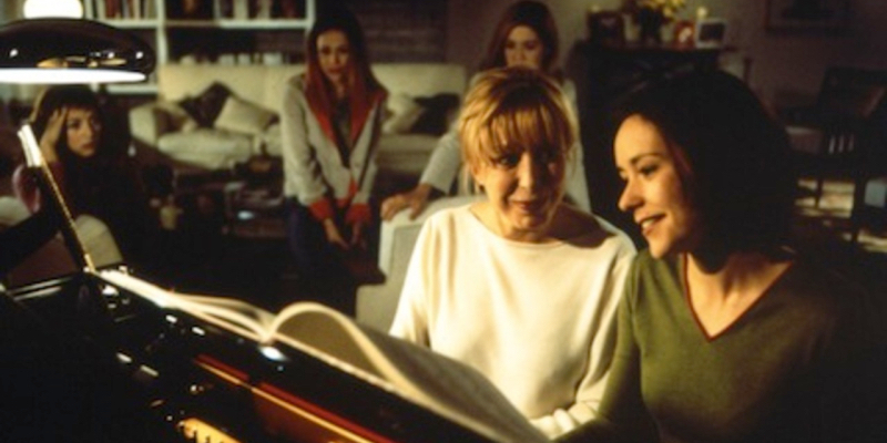 Two women sit on a piano bench together.