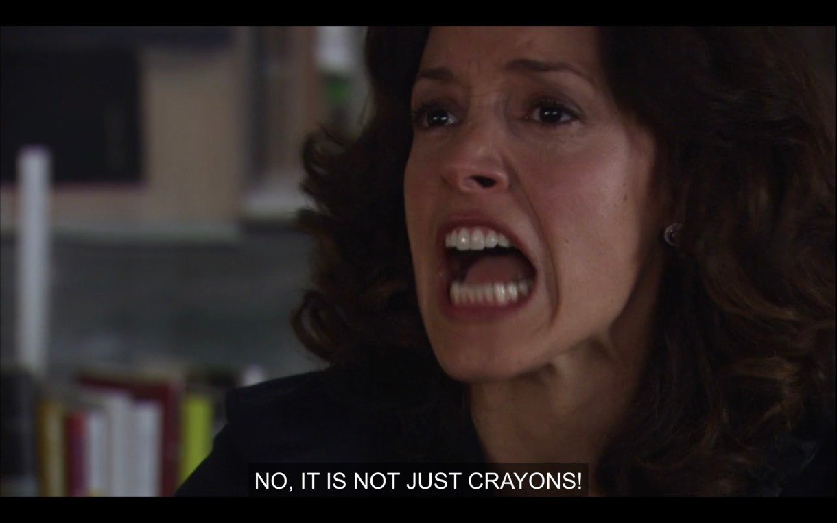 Bette sits at her office desk and yells angrily, "No, it is not just crayons!"