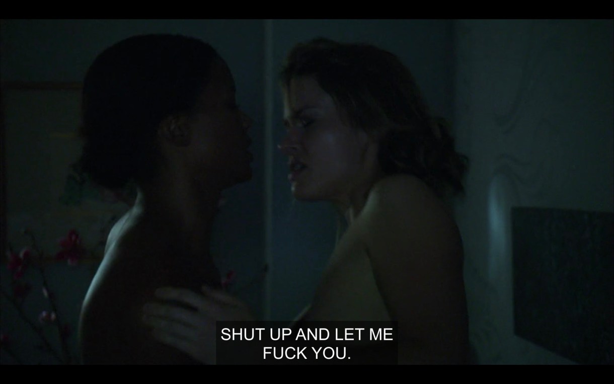 Tasha and Alice, naked in a dark room, their hands on each others' chests. Alice says, "Shut up and let me fuck you."