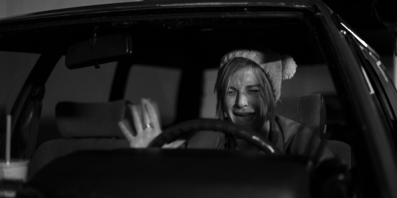 A woman cries behind the wheel of a car.