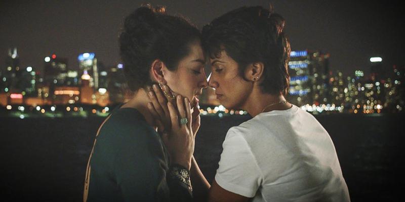 Fawzia Mirza rests her head against a woman with the city behind them.