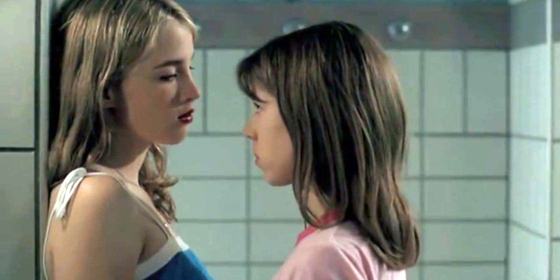 Two girls make eye contact in a school gym shower.