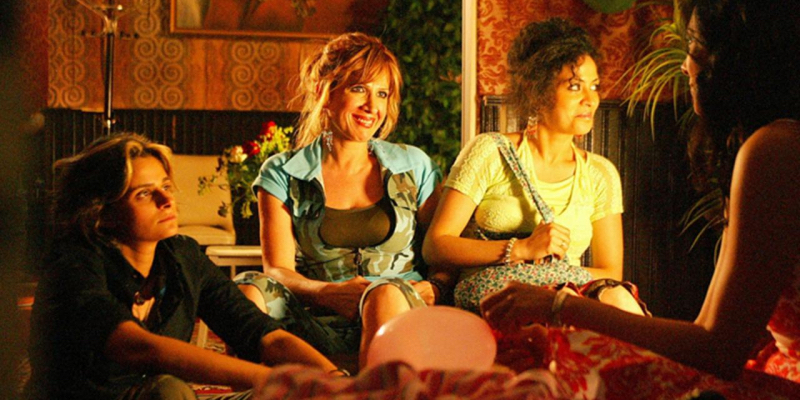 A group of women sit around in red lighting.