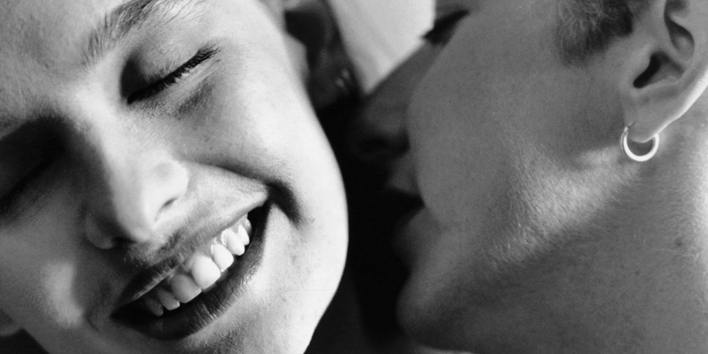 A close up of a woman kissing another woman's neck.