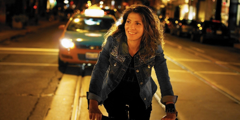 A woman smiles while riding her back around Toronto.