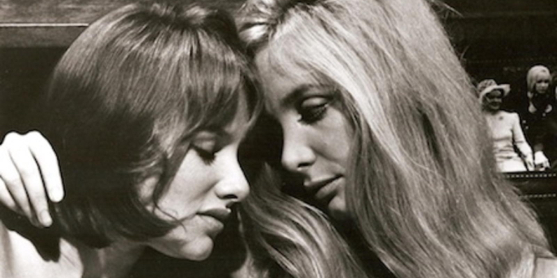 A black and white image of two women leaning their heads against each other.