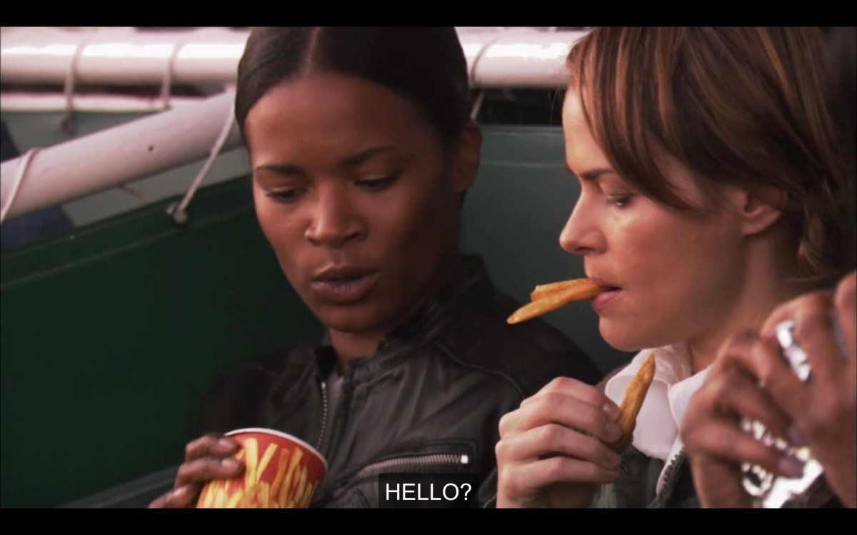 Tasha holding an empty cup of fries, next to Alice who has two fries sticking out of her mouth. Tasha says, "Hello?"