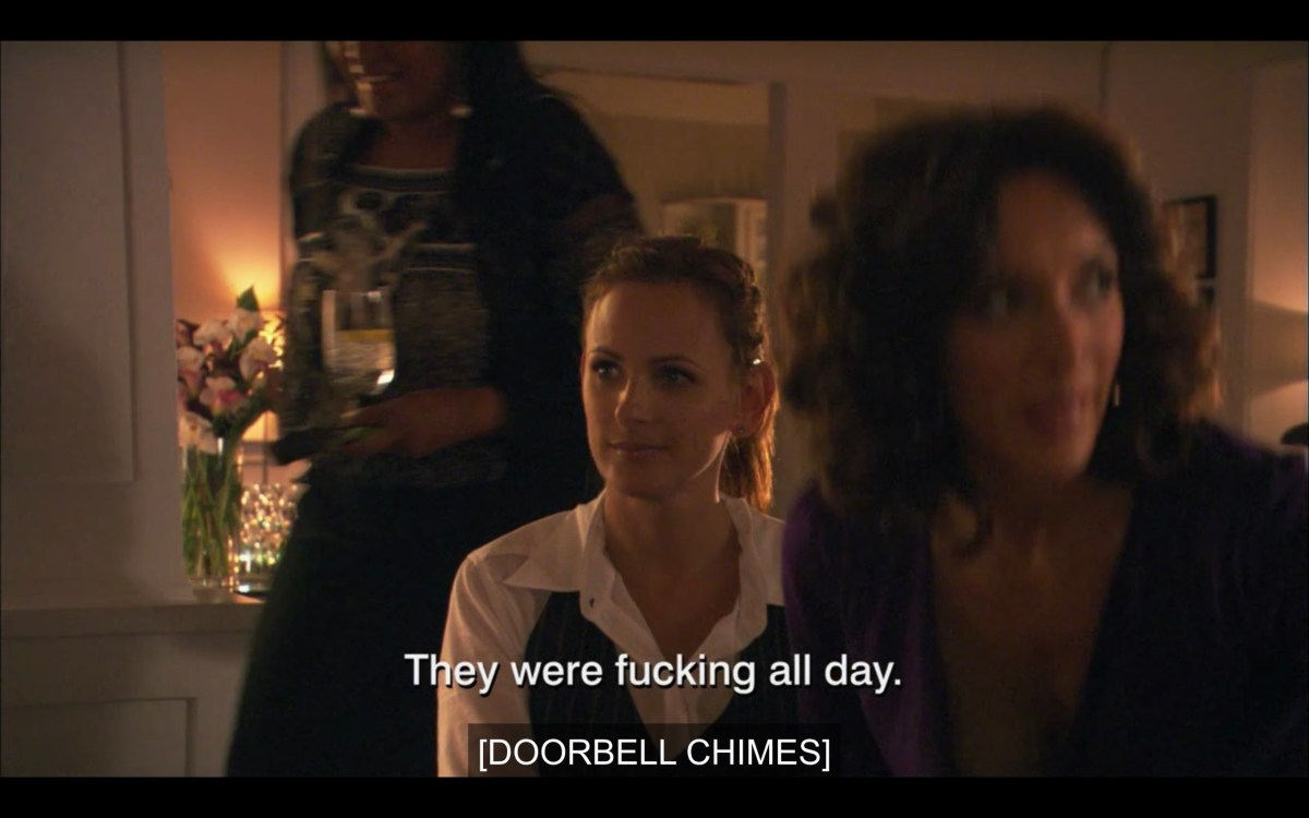 Jodi and Bette sitting together on a couch. Subtitles read, "They were fucking all day. [Doorbell chimes]"