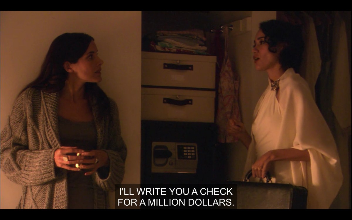 Helena (wearing a brown oversized cardigan) and Catherine (in a white poncho) face each other in a dimly lit room. Catherine is holding a brief case in her left hand. Catherine says, "I'll write you a check for a million dollars."