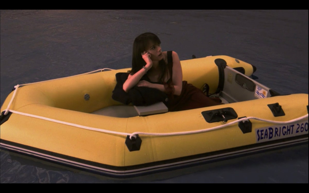 Jenny sits alone in an inflatable yellow boat in the water, resting her head in her hands.