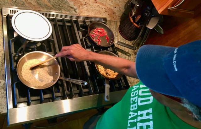 overhead shot of a South Indian dad in a baseball cap stirring toasting urad dal at a stove top for his gunpowder recipe