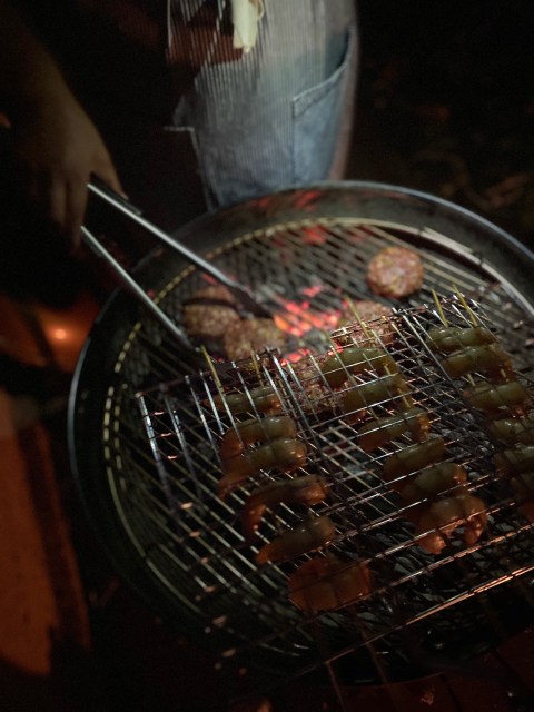 person at bbq turning patties over with tongs