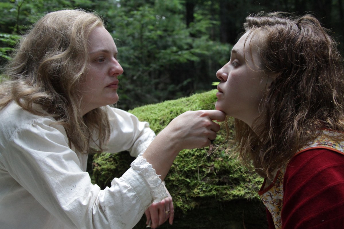 A film still from Shirley in which Elisabeth Moss's character cups the face of Odessa Young's character, who looks vulnerable and distraught