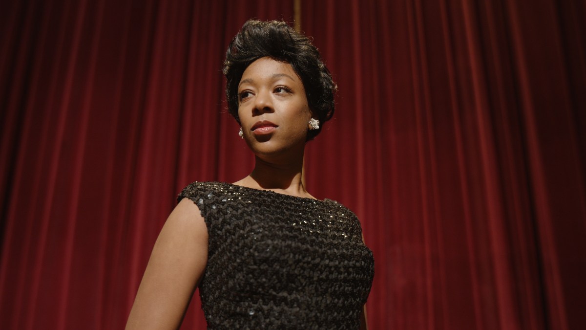 Samira Wiley as Lorraine Hannsberry, wearing a black shimmery dress in front of a red curtain