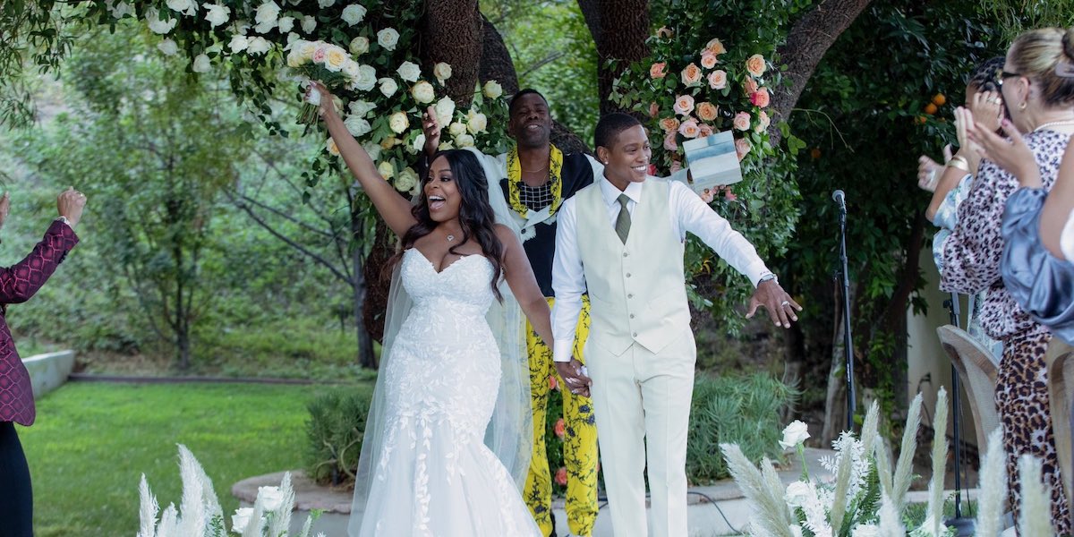 Niecy Nash getting gay married to new wife Jessica Betts. Niecy is in a white mermaid gone and Jessica wears a white suit and matching sneakers.