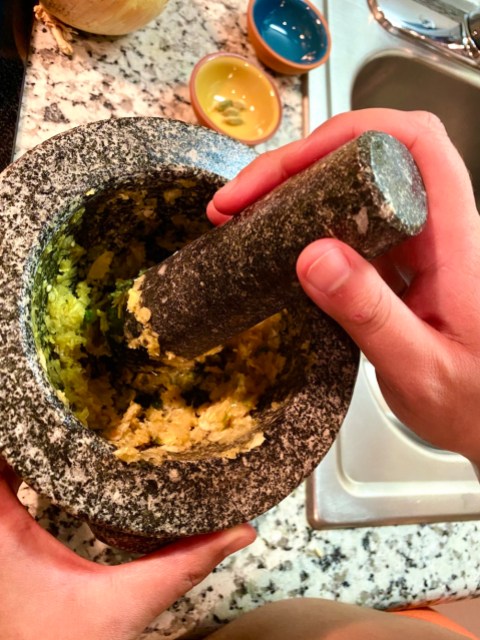 a green and white paste getting smashed up in a mortar and pestle